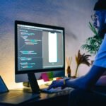 How React is Transforming The Web and Mobile Development young man mobile developer writes program code on 3fbnk5r